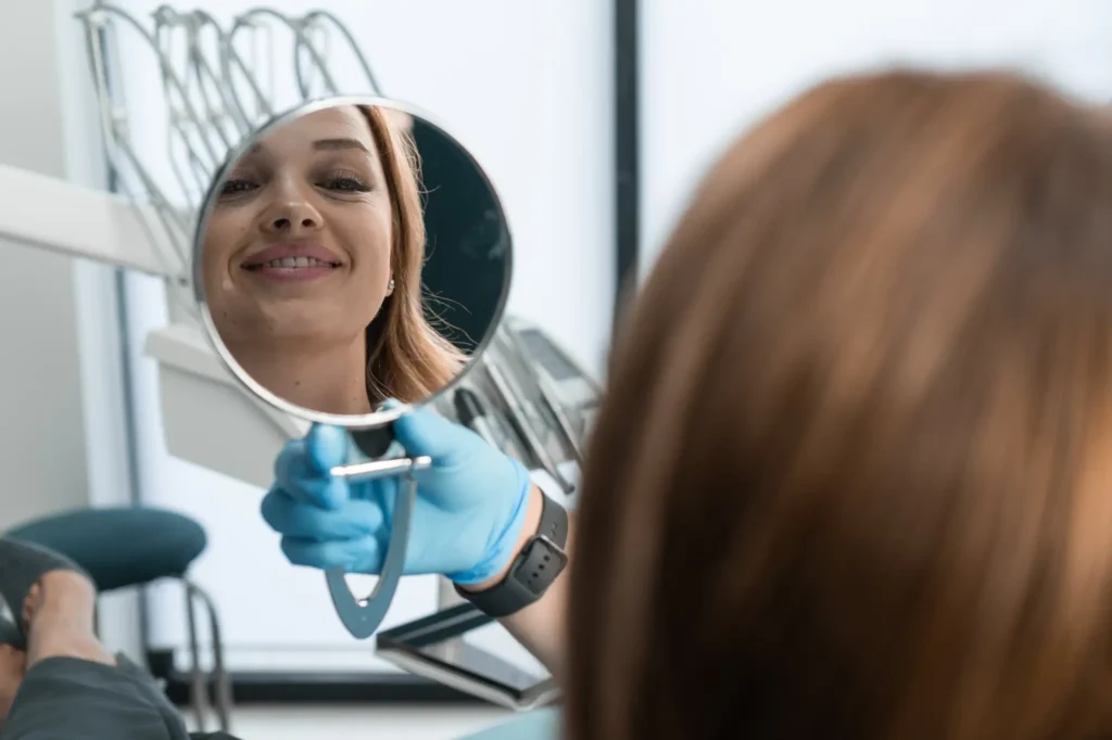 Female patient checking her restored smile in a mirror after receiving a tooth-colored filling at Southtown Family Dental in Kansas City, MO.