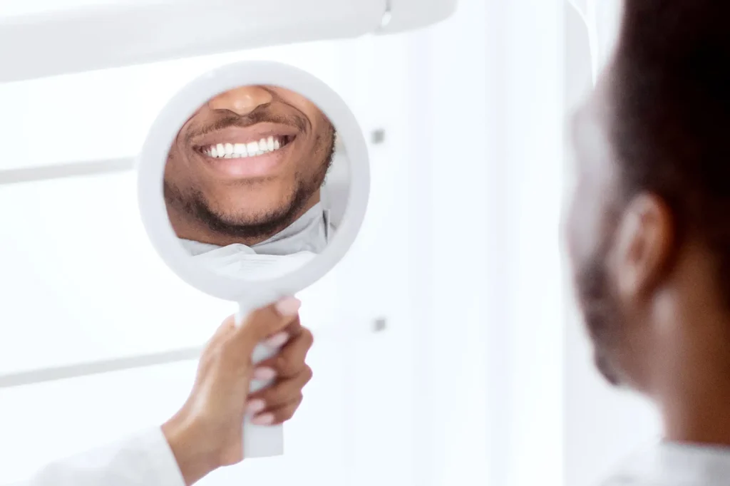 Patient admiring their bright smile in a dental mirror after a routine cleaning at Southtown Family Dental in Kansas City, MO.