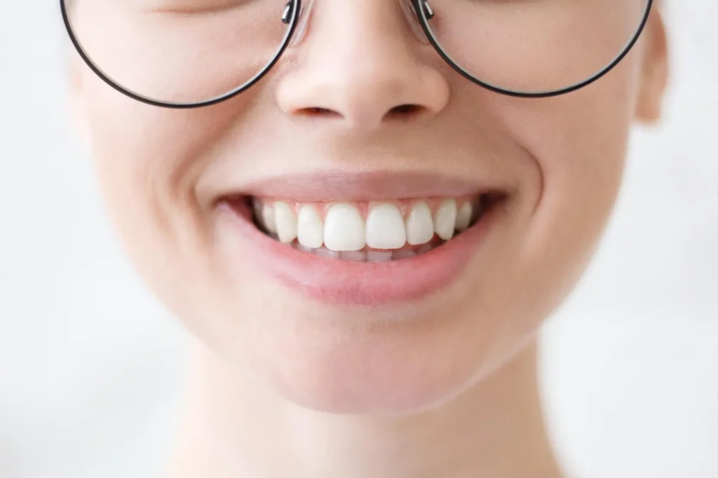 Close-up of a person wearing glasses and showing healthy, well-aligned teeth from Southtown Family Dental in Kansas City, MO.
