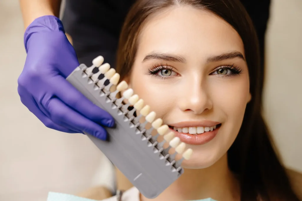 Smiling woman comparing tooth shades during a veneers consultation at Southtown Family Dental in Kansas City, MO.