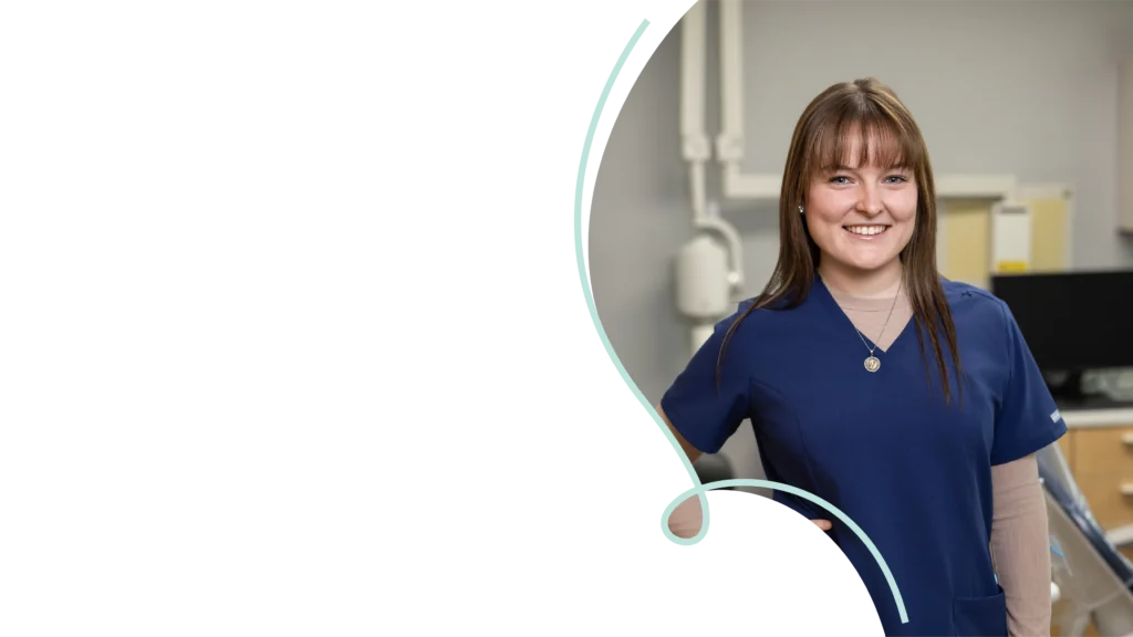 Team member at Southtown Family Dental in Kansas City, MO, wearing blue scrubs and smiling in a bright treatment room.
