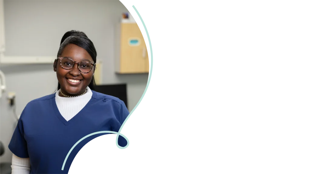 Dental assistant at Southtown Family Dental in Kansas City, MO, smiling warmly in a blue uniform inside the operatory.