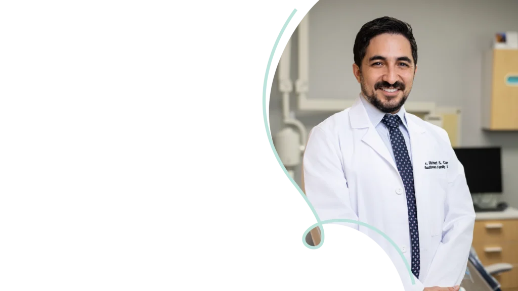 Dr. Richard Campos smiling in a white coat at Southtown Family Dental’s modern South Kansas City office.