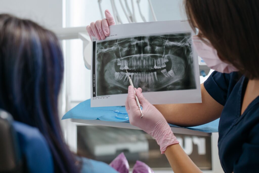 Dentist reviewing a dental X-ray with a patient to determine whether a severely decayed tooth can be restored with personalized treatment.